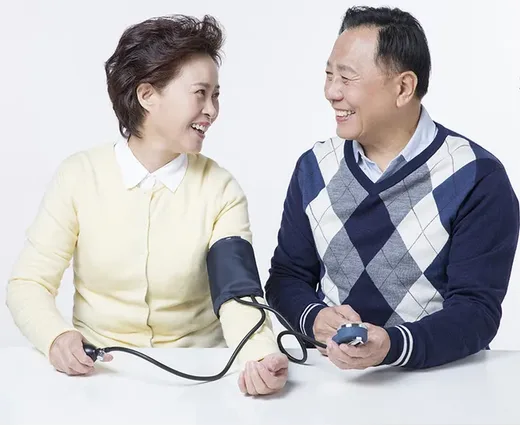 혈압을 재며 마주 보고 웃는 중년 부부