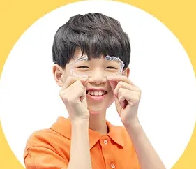 볼을 잡아당기며 웃는 남자아이